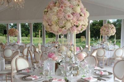Décoration de table de réception avec nappes blanches, chandeliers, vaisselle élégante et arrangement floral blanc.
