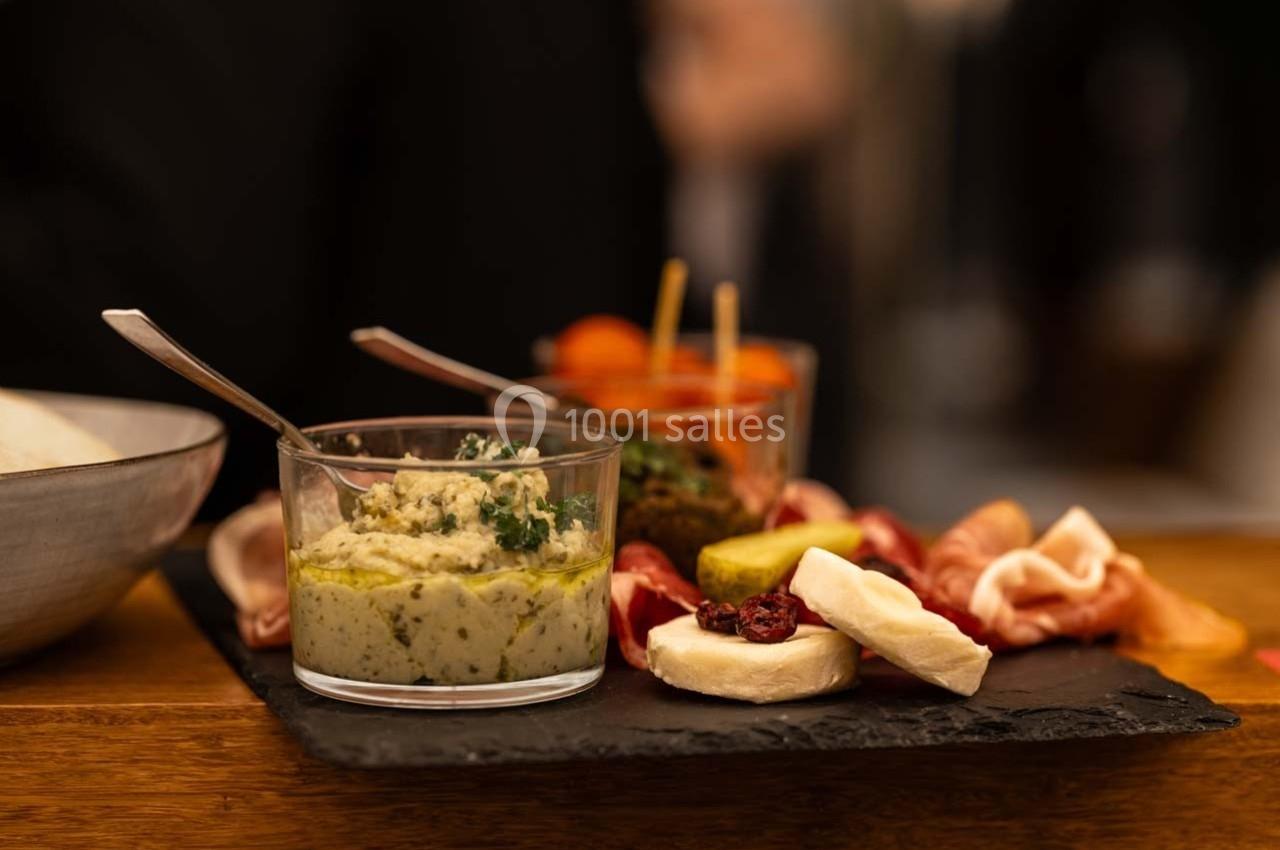 Plateau apéritif avec charcuterie, fromage, légumes marinés et verrines de tartinades sur une ardoise noire.