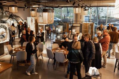 Un café moderne avec un comptoir en bois, des tabourets, des clients et des baristas en pleine discussion.