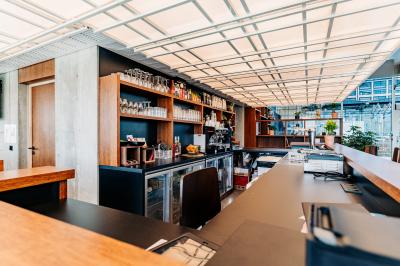 Un café moderne avec un comptoir en bois, des tabourets, des clients et des baristas en pleine discussion.