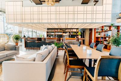 Un café moderne avec un comptoir en bois, des tabourets, des clients et des baristas en pleine discussion.