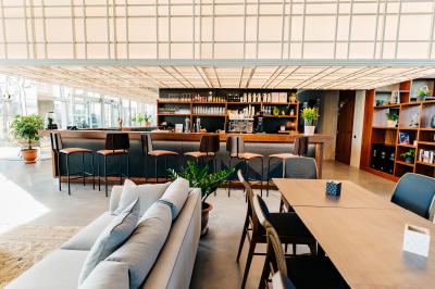 Un café moderne avec un comptoir en bois, des tabourets, des clients et des baristas en pleine discussion.