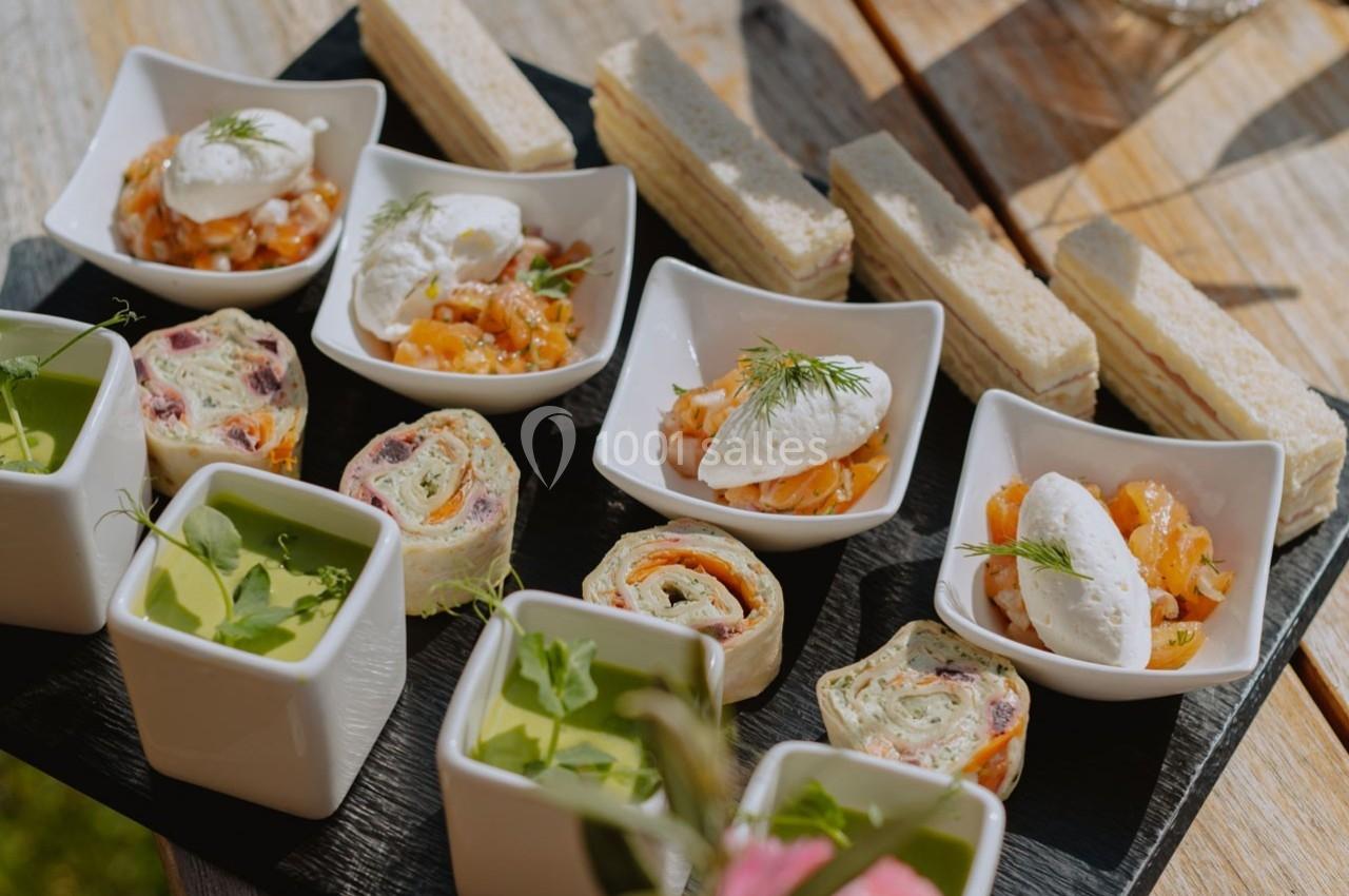 Plateau de bouchées apéritives variées, incluant verrines, roulés, toasts et bols garnis de crème et aneth.