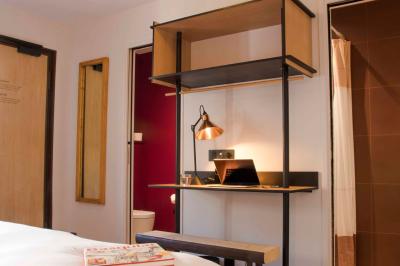 Bureau en bois avec lampe, ordinateur portable et étagères, situé entre deux portes dans une chambre lumineuse.