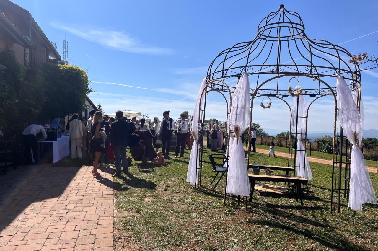 Groupe de personnes rassemblées en extérieur près d'une structure métallique décorée de voilages blancs.