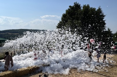 Tentes modernes installées sur une pelouse près d'une tour de communication sous un ciel partiellement nuageux.