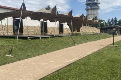 Tentes modernes installées sur une pelouse près d'une tour de communication sous un ciel partiellement nuageux.