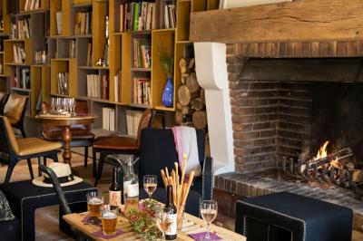 Salon chaleureux avec cheminée allumée, table basse garnie de boissons et snacks, entourée de fauteuils et étagères de…