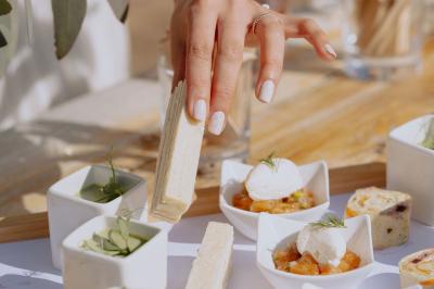 Salon chaleureux avec cheminée allumée, table basse garnie de boissons et snacks, entourée de fauteuils et étagères de…
