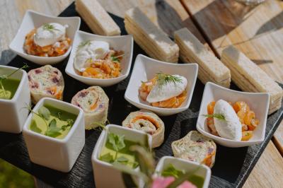 Salon chaleureux avec cheminée allumée, table basse garnie de boissons et snacks, entourée de fauteuils et étagères de…