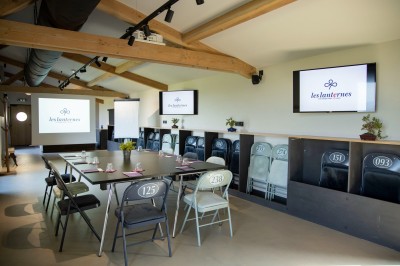 Salon chaleureux avec cheminée allumée, table basse garnie de boissons et snacks, entourée de fauteuils et étagères de…