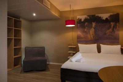 Espace lounge avec fauteuils modernes, tables basses en bois et mur décoré d'une image d'échiquier.