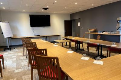 Espace lounge avec fauteuils modernes, tables basses en bois et mur décoré d'une image d'échiquier.