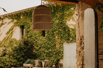 Cour intérieure avec murs recouverts de lierre, une porte en bois ouverte, un tonneau et une lanterne suspendue.