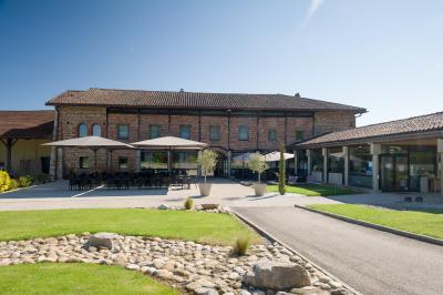 Chambre avec lit double, mur décoré de papier peint tropical, poutre apparente et grande fenêtre avec rideaux beiges.