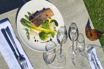 Chambre avec lit double, mur décoré de papier peint tropical, poutre apparente et grande fenêtre avec rideaux beiges.