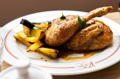 Assiette contenant un poisson entier grillé, des légumes rôtis variés et une sauce servie sur une table en marbre.