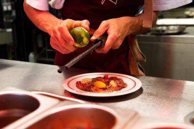 Assiette contenant un poisson entier grillé, des légumes rôtis variés et une sauce servie sur une table en marbre.