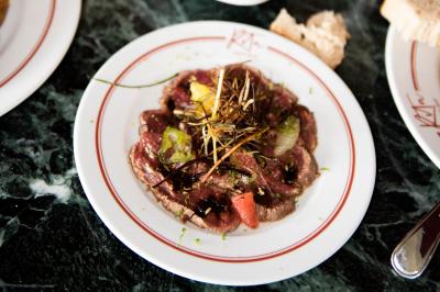 Assiette contenant un poisson entier grillé, des légumes rôtis variés et une sauce servie sur une table en marbre.