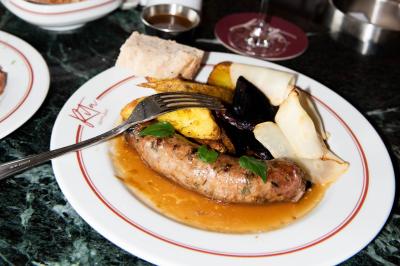 Assiette contenant un poisson entier grillé, des légumes rôtis variés et une sauce servie sur une table en marbre.