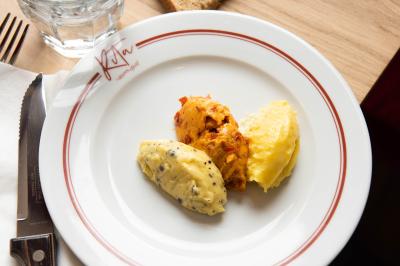 Des personnes assises à des tables dans un restaurant lumineux, discutant et partageant un repas près de grandes fenêtres.