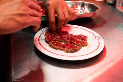 Des personnes assises à des tables dans un restaurant lumineux, discutant et partageant un repas près de grandes fenêtres.
