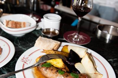 Des personnes assises à des tables dans un restaurant lumineux, discutant et partageant un repas près de grandes fenêtres.