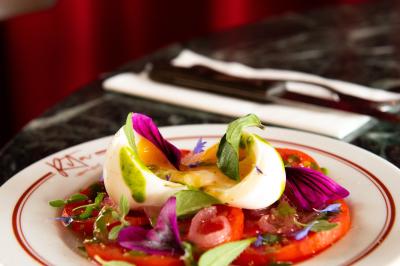 Des personnes assises à des tables dans un restaurant lumineux, discutant et partageant un repas près de grandes fenêtres.