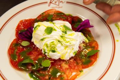Des personnes assises à des tables dans un restaurant lumineux, discutant et partageant un repas près de grandes fenêtres.