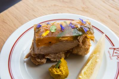 Des personnes assises à des tables dans un restaurant lumineux, discutant et partageant un repas près de grandes fenêtres.
