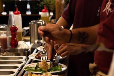 Des personnes assises à des tables dans un restaurant lumineux, discutant et partageant un repas près de grandes fenêtres.
