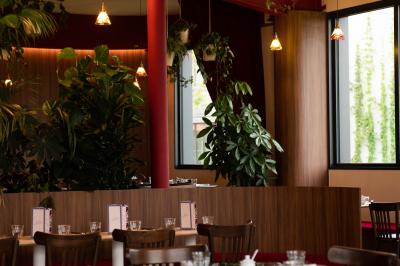 Des personnes assises à des tables dans un restaurant lumineux, discutant et partageant un repas près de grandes fenêtres.