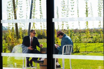 Des personnes assises à des tables dans un restaurant lumineux, discutant et partageant un repas près de grandes fenêtres.