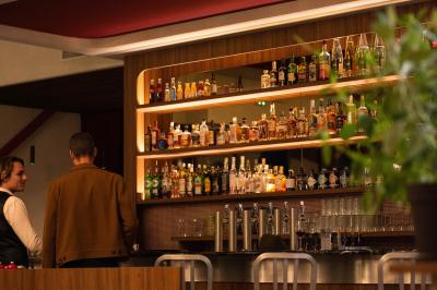 Des personnes assises à des tables dans un restaurant lumineux, discutant et partageant un repas près de grandes fenêtres.