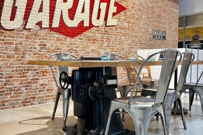 Tables hautes noires dans une salle avec un mur décoré d'une photo de voiture de course vintage.