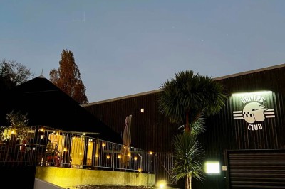 Tables hautes noires dans une salle avec un mur décoré d'une photo de voiture de course vintage.