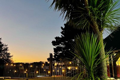Tables hautes noires dans une salle avec un mur décoré d'une photo de voiture de course vintage.