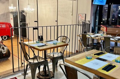 Tables hautes noires dans une salle avec un mur décoré d'une photo de voiture de course vintage.