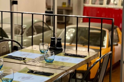 Tables hautes noires dans une salle avec un mur décoré d'une photo de voiture de course vintage.