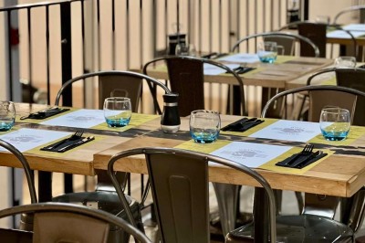 Tables hautes noires dans une salle avec un mur décoré d'une photo de voiture de course vintage.