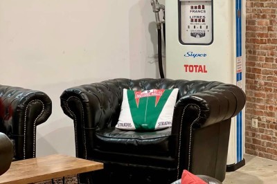 Tables hautes noires dans une salle avec un mur décoré d'une photo de voiture de course vintage.