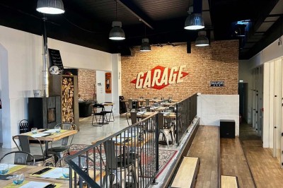 Tables hautes noires dans une salle avec un mur décoré d'une photo de voiture de course vintage.