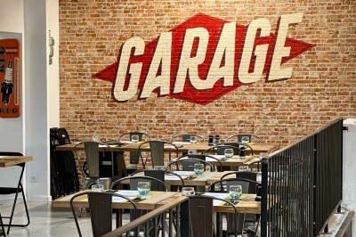 Tables hautes noires dans une salle avec un mur décoré d'une photo de voiture de course vintage.