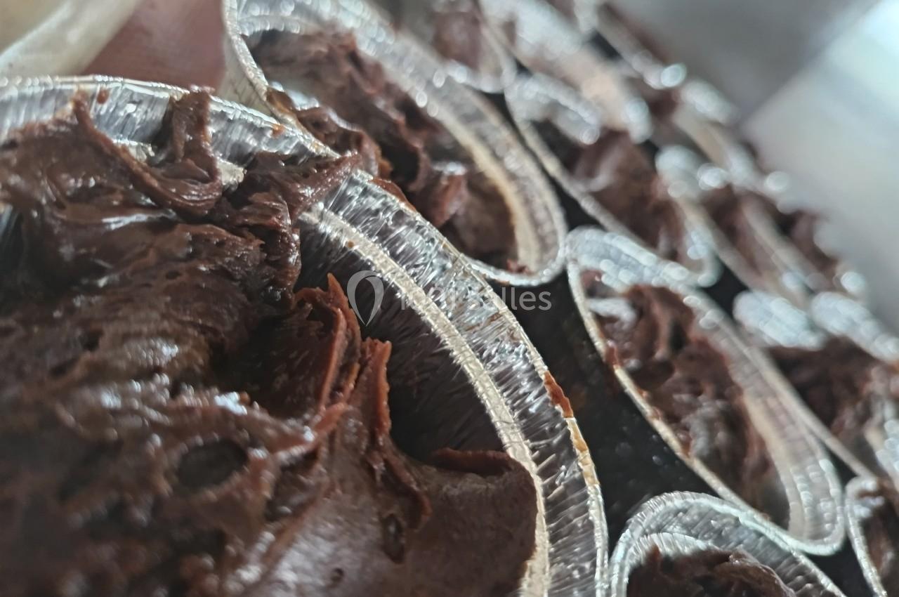 Pots en aluminium remplis de pâte au chocolat épaisse, alignés sur une surface.