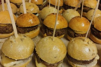 Plateau en bois avec verrines garnies, bol de pain tranché et bouteille de vin mousseux en arrière-plan.