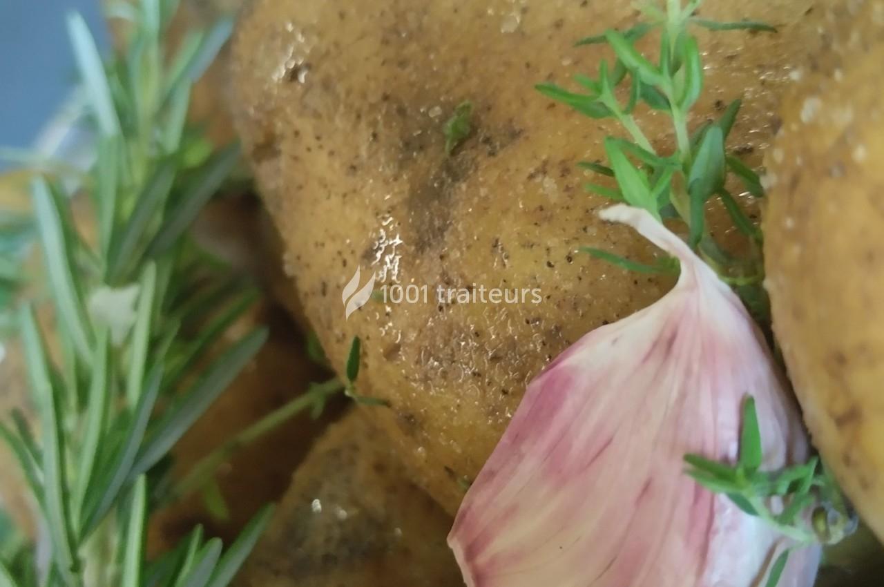 Pommes de terre assaisonnées avec des herbes fraîches, une gousse d'ail et des brins de romarin.