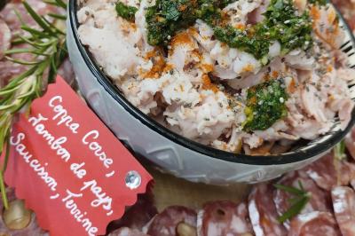 Plateau en bois avec verrines garnies, bol de pain tranché et bouteille de vin mousseux en arrière-plan.