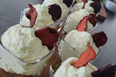 Plateau en bois avec verrines garnies, bol de pain tranché et bouteille de vin mousseux en arrière-plan.