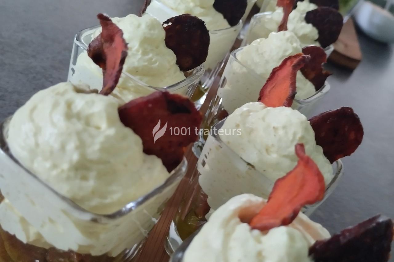 Verrines garnies de mousse blanche et décorées de chips de betterave rouge sur une table sombre.
