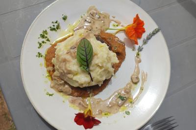 Plateau en bois avec verrines garnies, bol de pain tranché et bouteille de vin mousseux en arrière-plan.